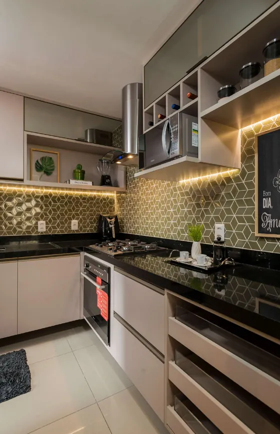 Cozinha com revestimento verde, bancada preta e iluminação sob os armários