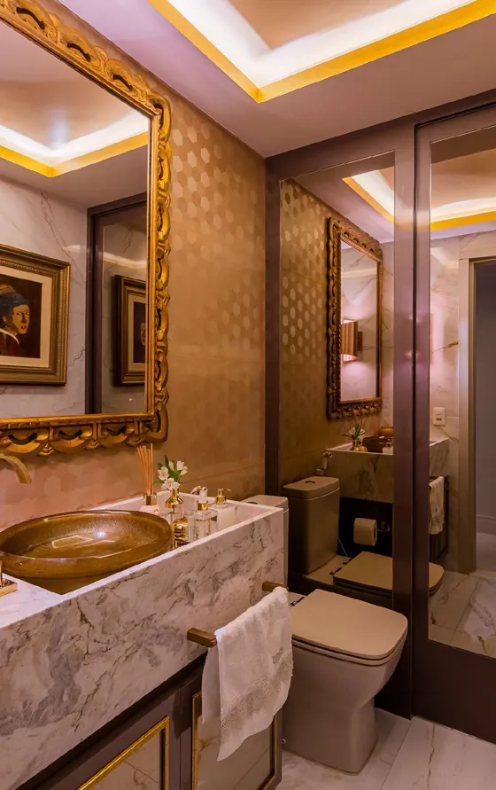 Lavabo com espelho de moldura dourada, cuba de pedra e revestimento texturizado