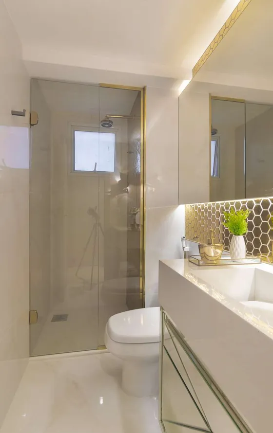 Banheiro claro com box de vidro e bancada com revestimento hexagonal