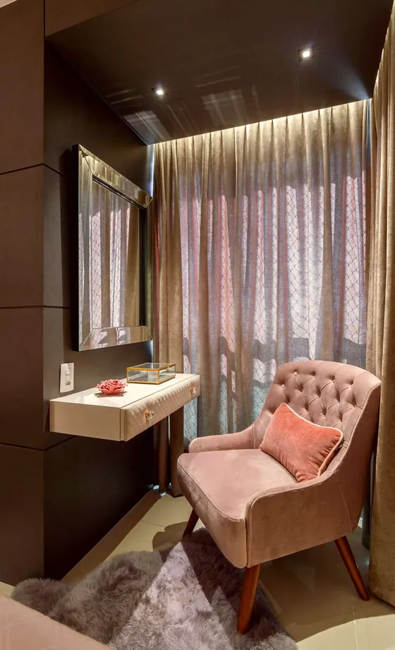 Canto do quarto com poltrona capitonê rosa, penteadeira e cortina
