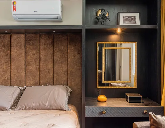 Quarto de hóspedes com cabeceira de couro, nicho iluminado e espelho dourado