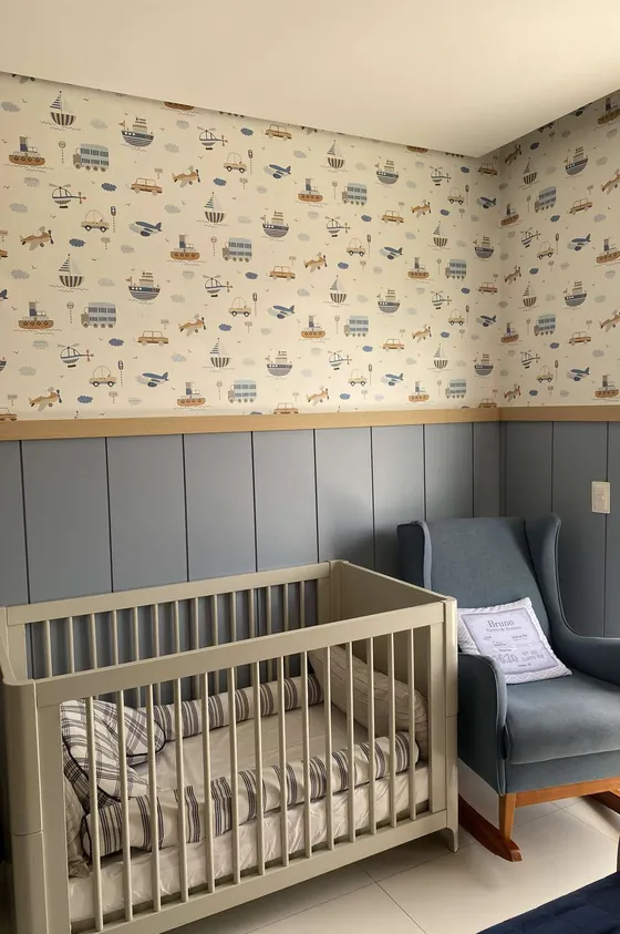 Quarto infantil com papel de parede de barquinhos, berço cinza e poltrona azul