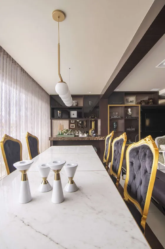Mesa de jantar de mármore com cadeiras de encosto dourado entalhado e estofado capitonê